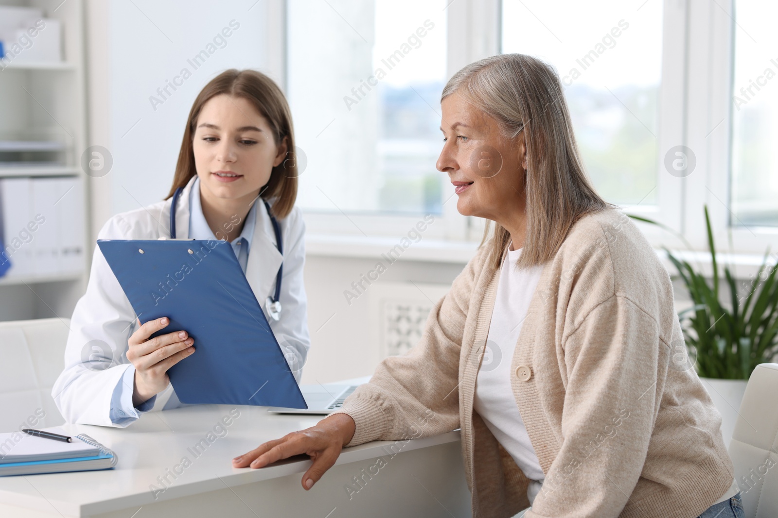 Photo of Healthcare worker and senior patient checking clipboard with analysis results in hospital