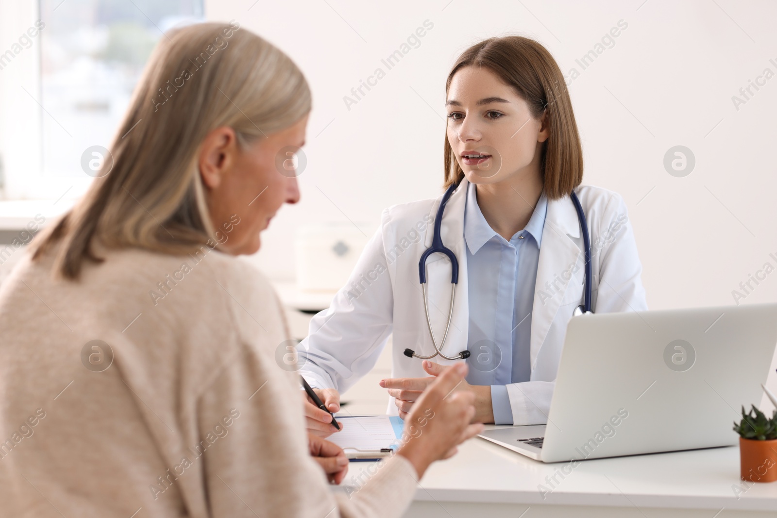 Photo of Young healthcare worker consulting senior patient in hospital