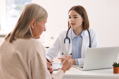 Young healthcare worker consulting senior patient in hospital