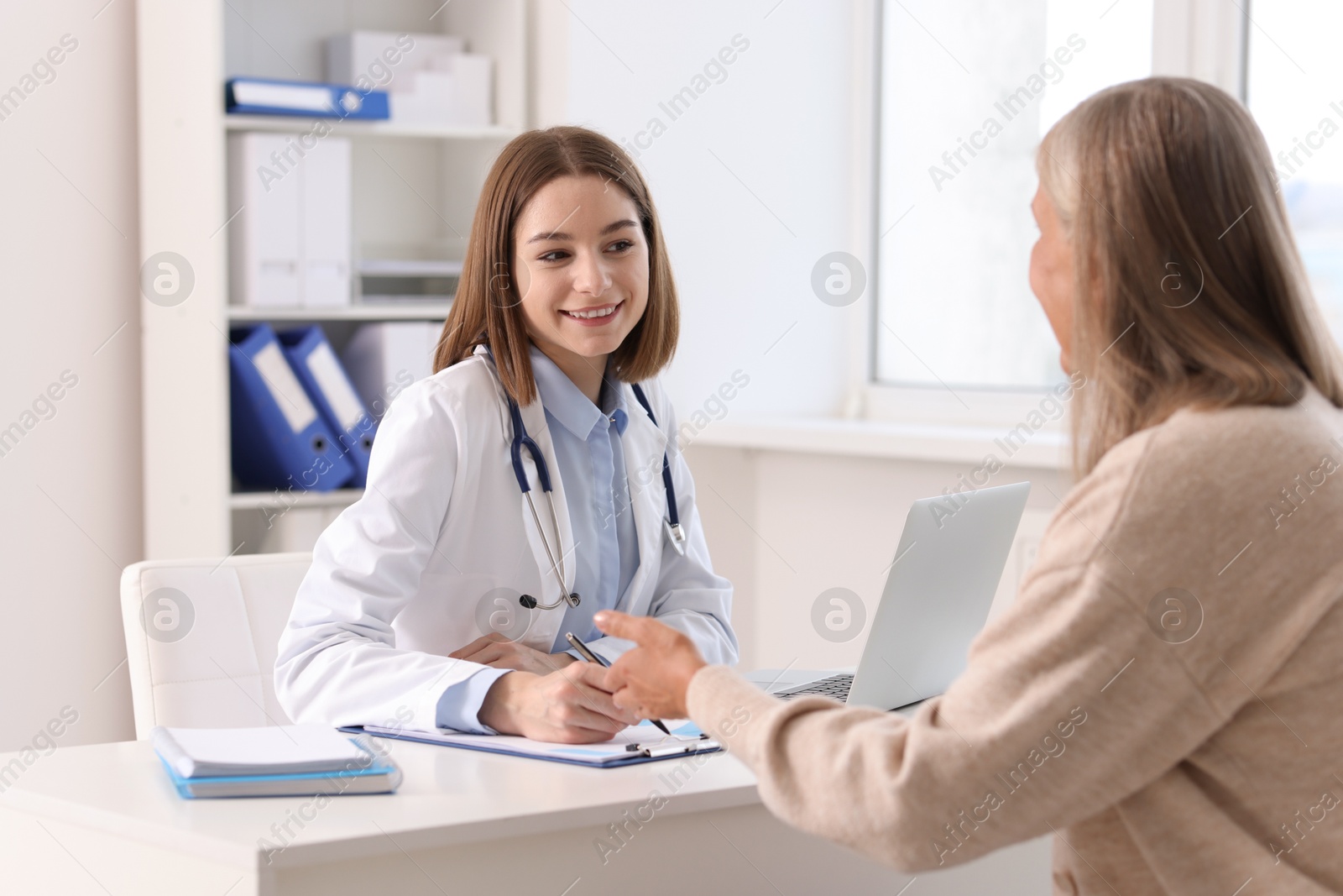 Photo of Smiling healthcare worker consulting senior patient in hospital