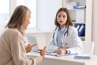 Photo of Young healthcare worker consulting senior patient in hospital