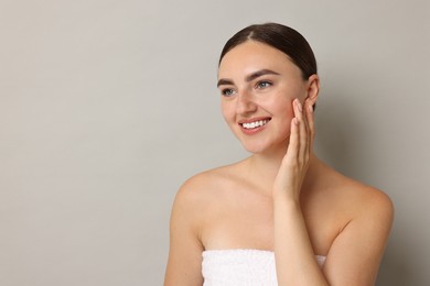 Beautiful young woman with healthy skin on grey background