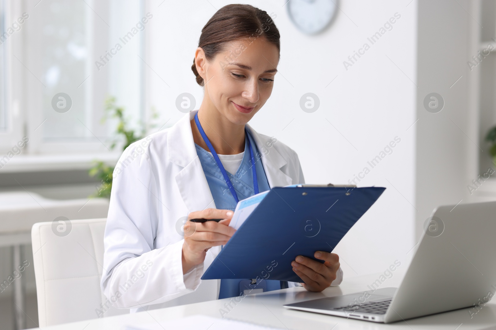 Photo of Nurse with clipboard and pen at white table in clinic