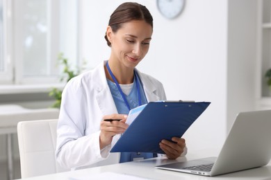 Nurse with clipboard and pen at white table in clinic