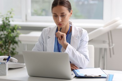 Photo of Nurse with pen working at white table in clinic