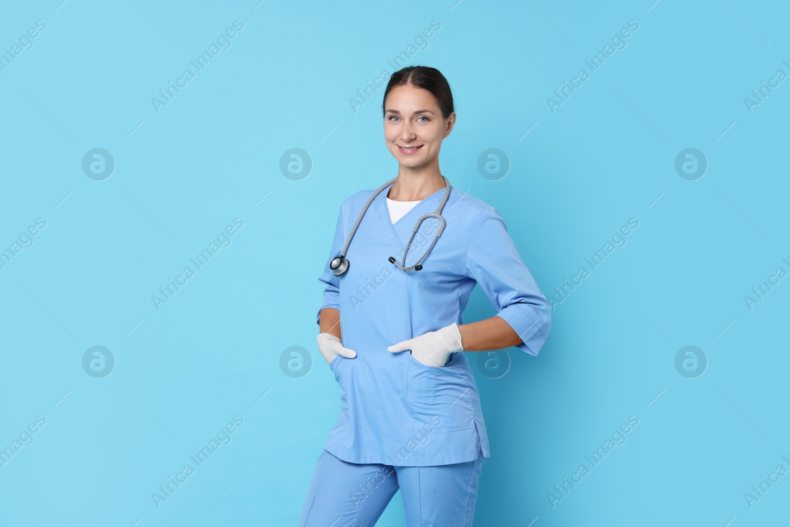 Photo of Nurse in medical uniform with stethoscope on light blue background