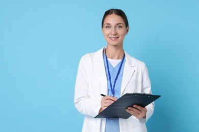 Photo of Nurse in medical uniform with clipboard on light blue background