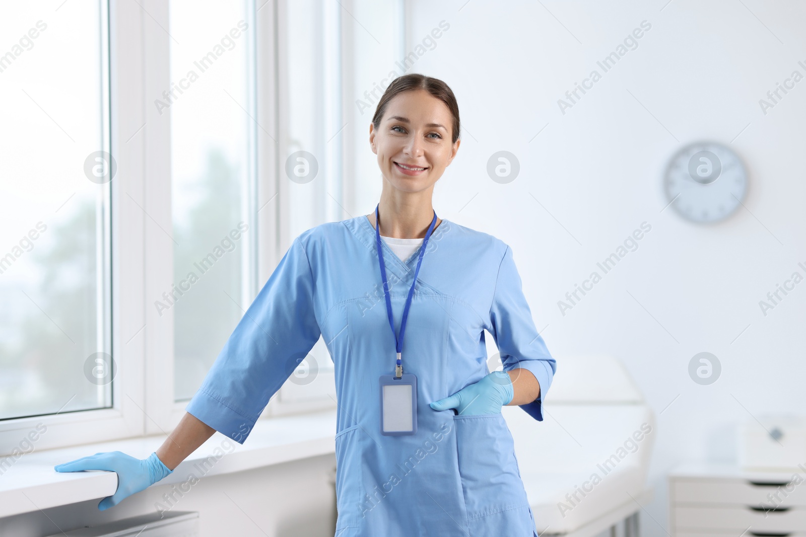 Photo of Nurse in medical uniform near window indoors