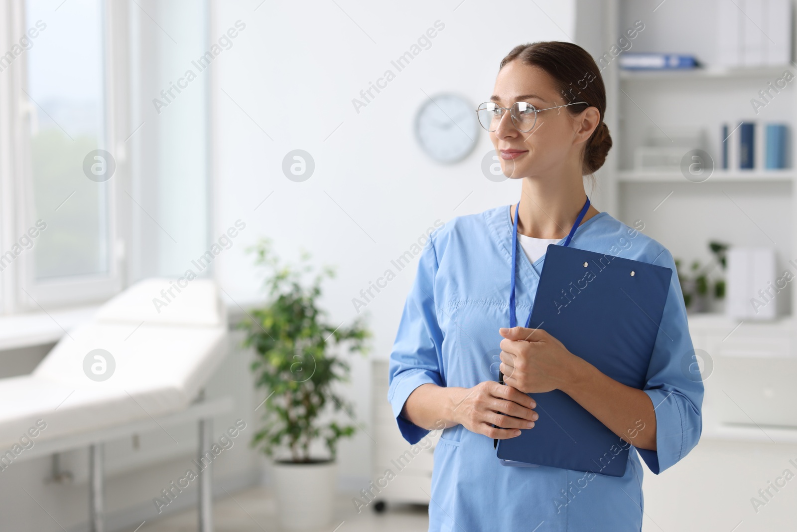 Photo of Nurse in medical uniform with clipboard indoors, space for text