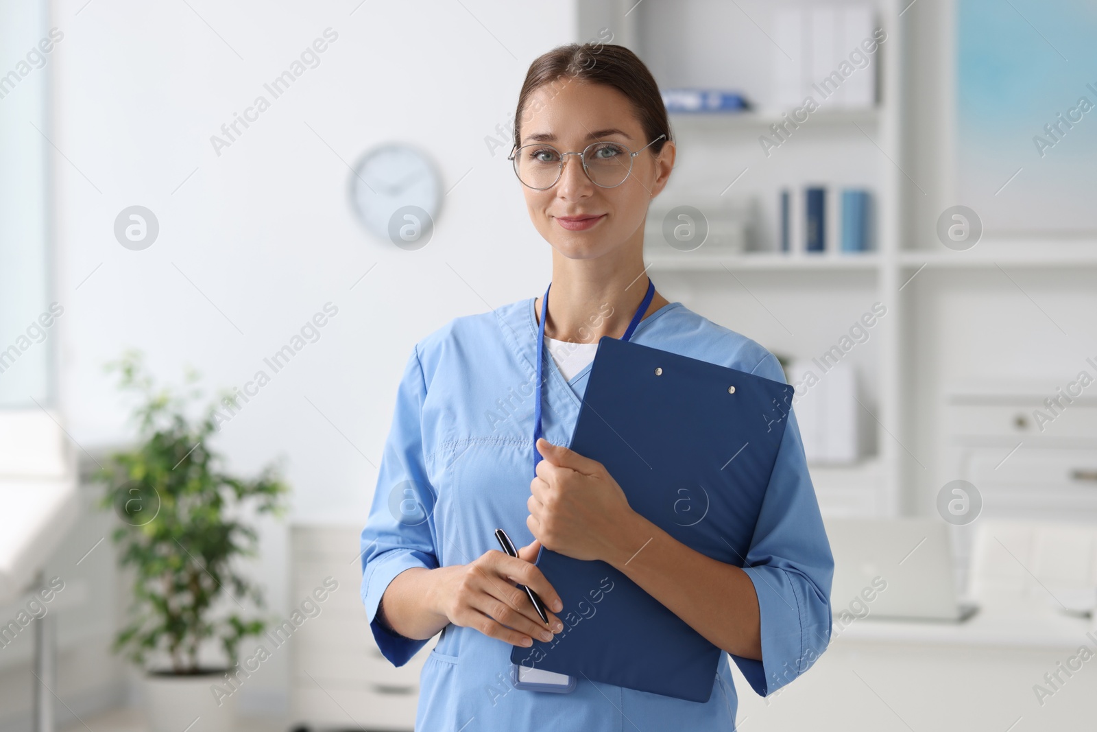 Photo of Nurse in medical uniform with clipboard indoors