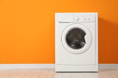 Photo of Washing machine near orange wall, space for text