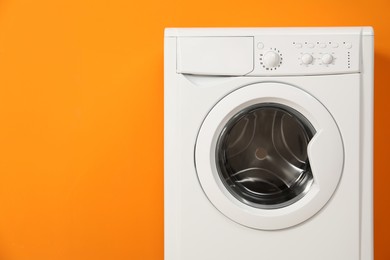 Photo of Washing machine near orange wall, space for text