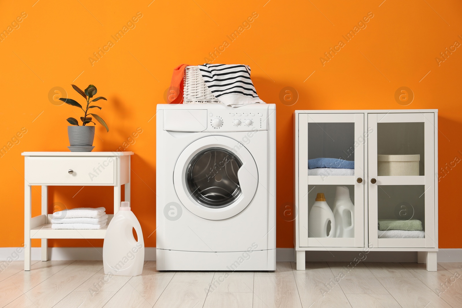 Photo of Washing machine, towels and detergents in laundry room