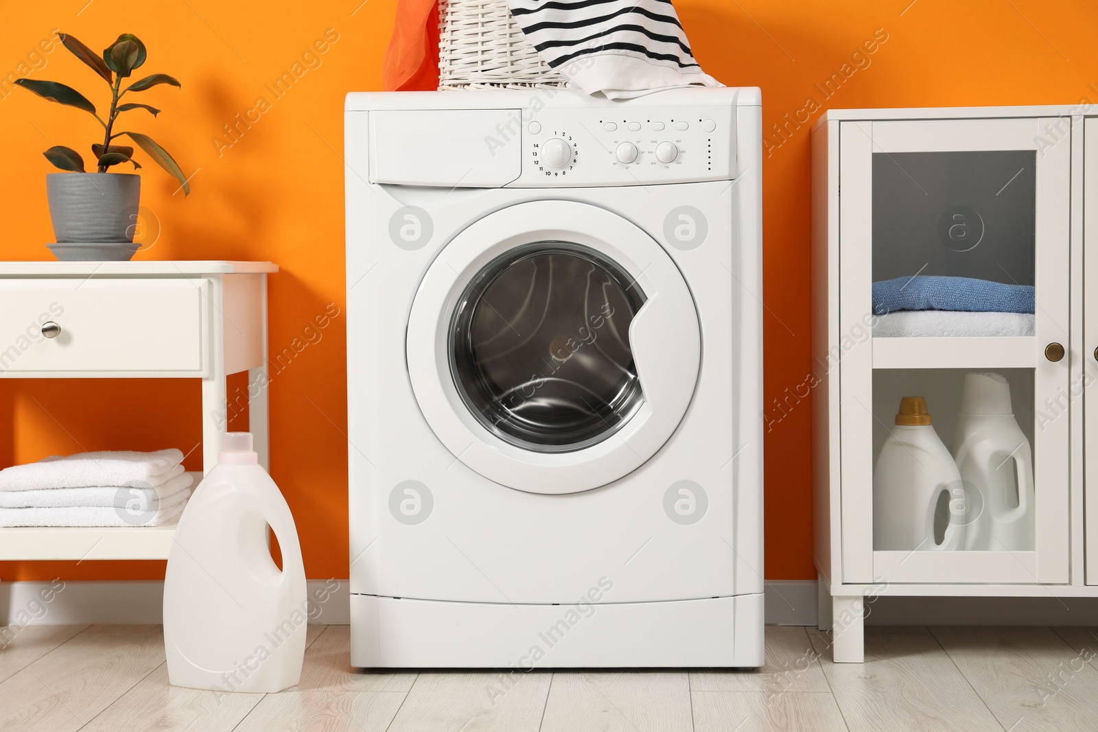 Photo of Washing machine, towels and detergents in laundry room