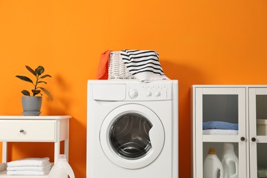 Photo of Washing machine, towels and detergents in laundry room