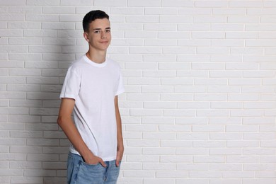 Photo of Teenage boy wearing t-shirt near white brick wall, space for text