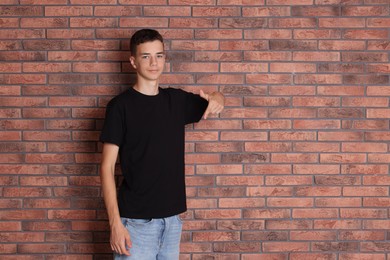 Photo of Teenage boy wearing black t-shirt near brick wall, space for text