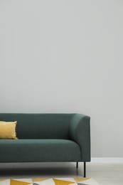 Photo of Comfortable sofa near light grey wall indoors, space for text