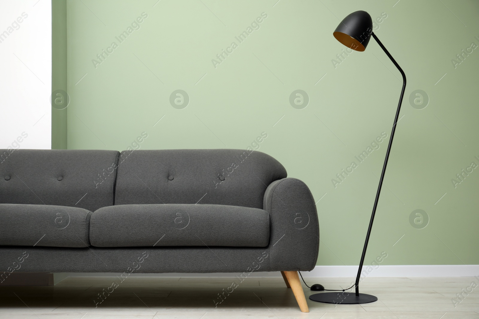 Photo of Stylish sofa and floor lamp in room. Interior design