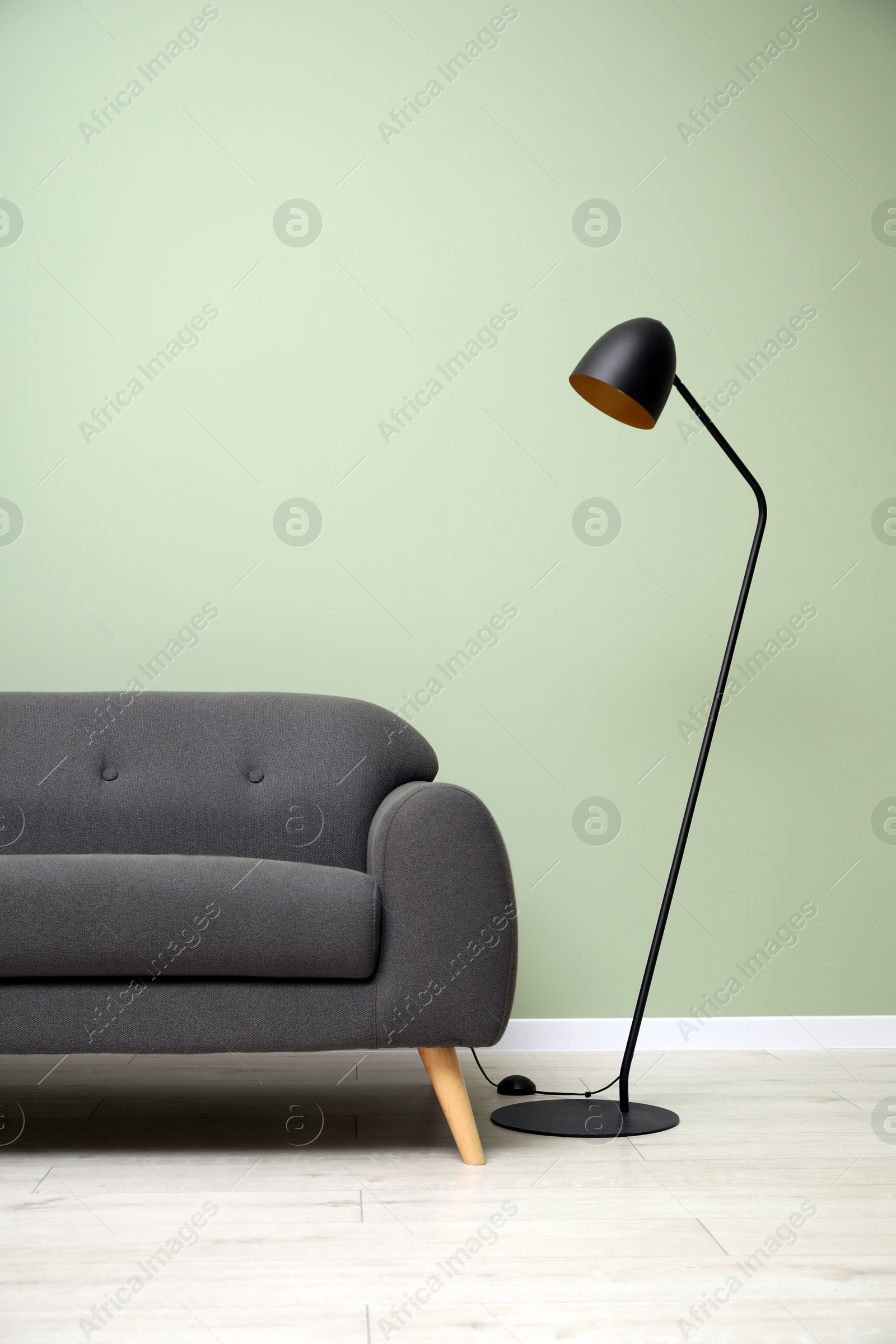 Photo of Stylish sofa and floor lamp in room. Interior design