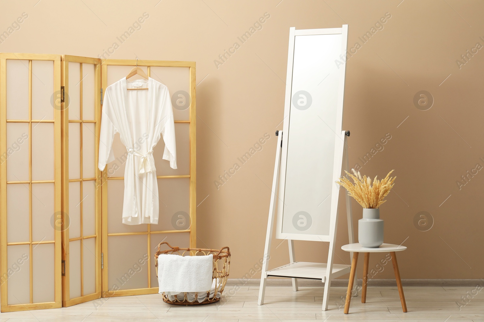 Photo of Large mirror near beige wall in bathroom. Interior design