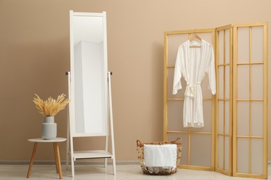 Photo of Large mirror near beige wall in bathroom. Interior design