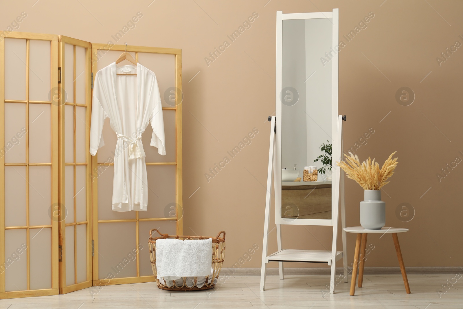 Photo of Large mirror near beige wall in bathroom. Interior design