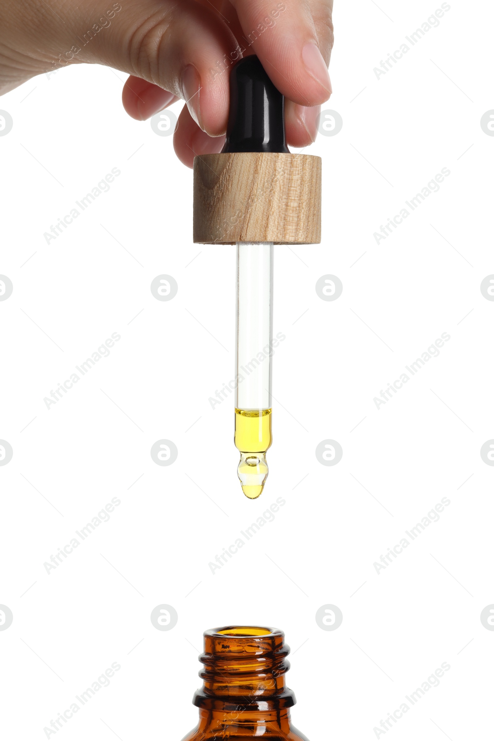 Photo of Woman dripping tincture from pipette into bottle on white background, closeup