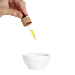 Photo of Woman dripping tincture from pipette into bowl on white background, closeup