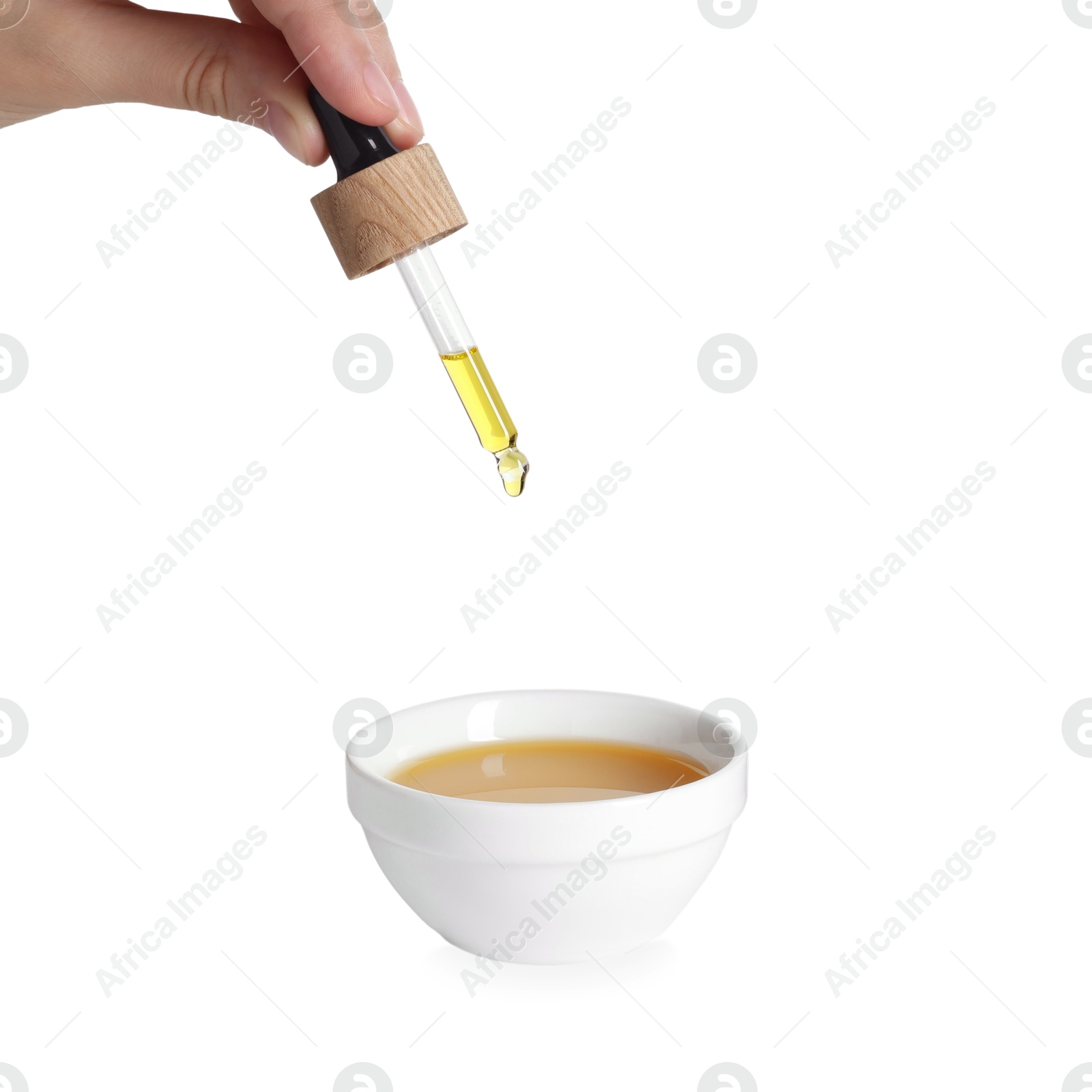 Photo of Woman dripping tincture from pipette into bowl on white background, closeup