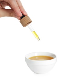 Photo of Woman dripping tincture from pipette into bowl on white background, closeup