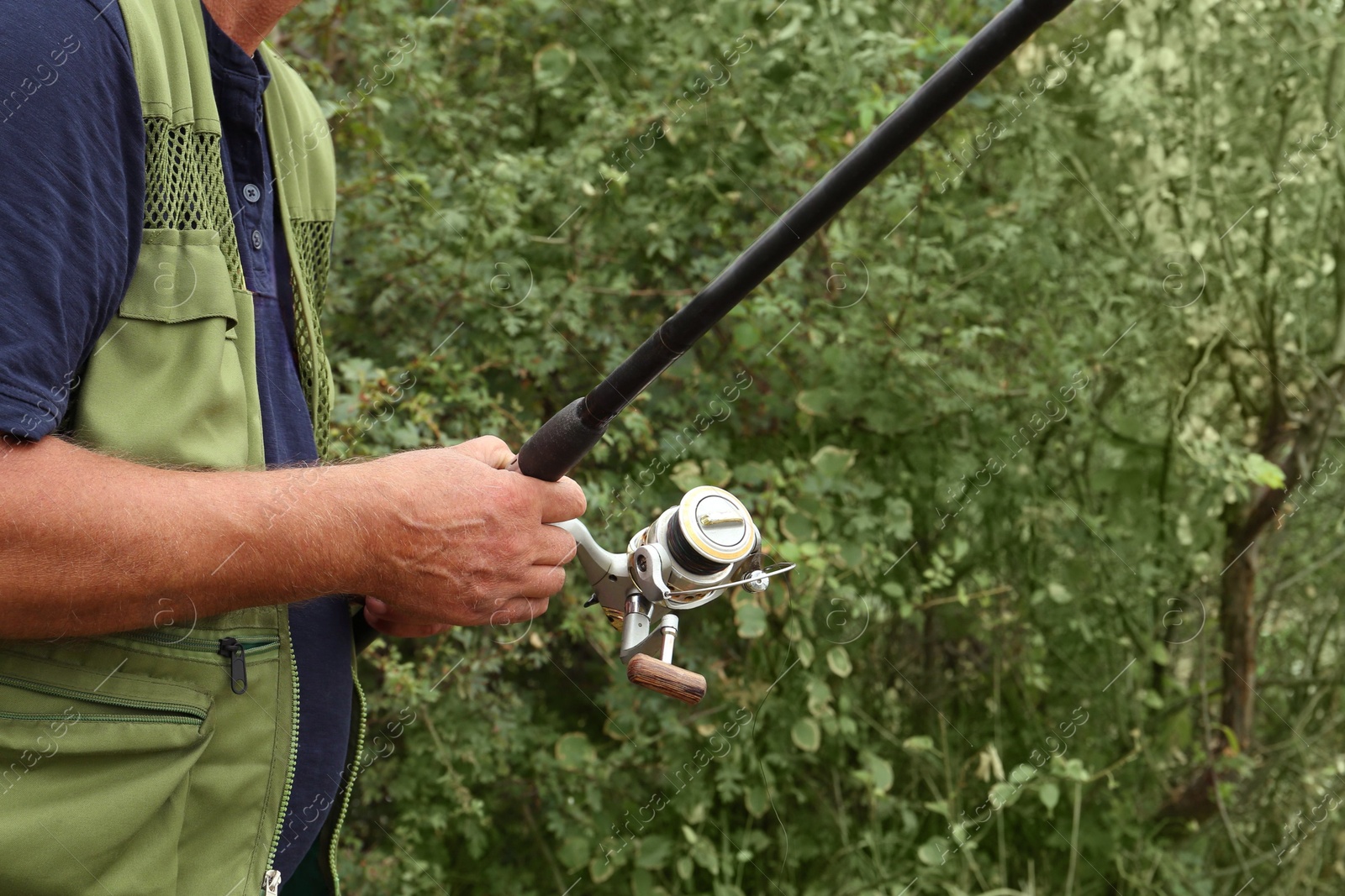 Photo of Fisherman with rod fishing near lake at summer, closeup