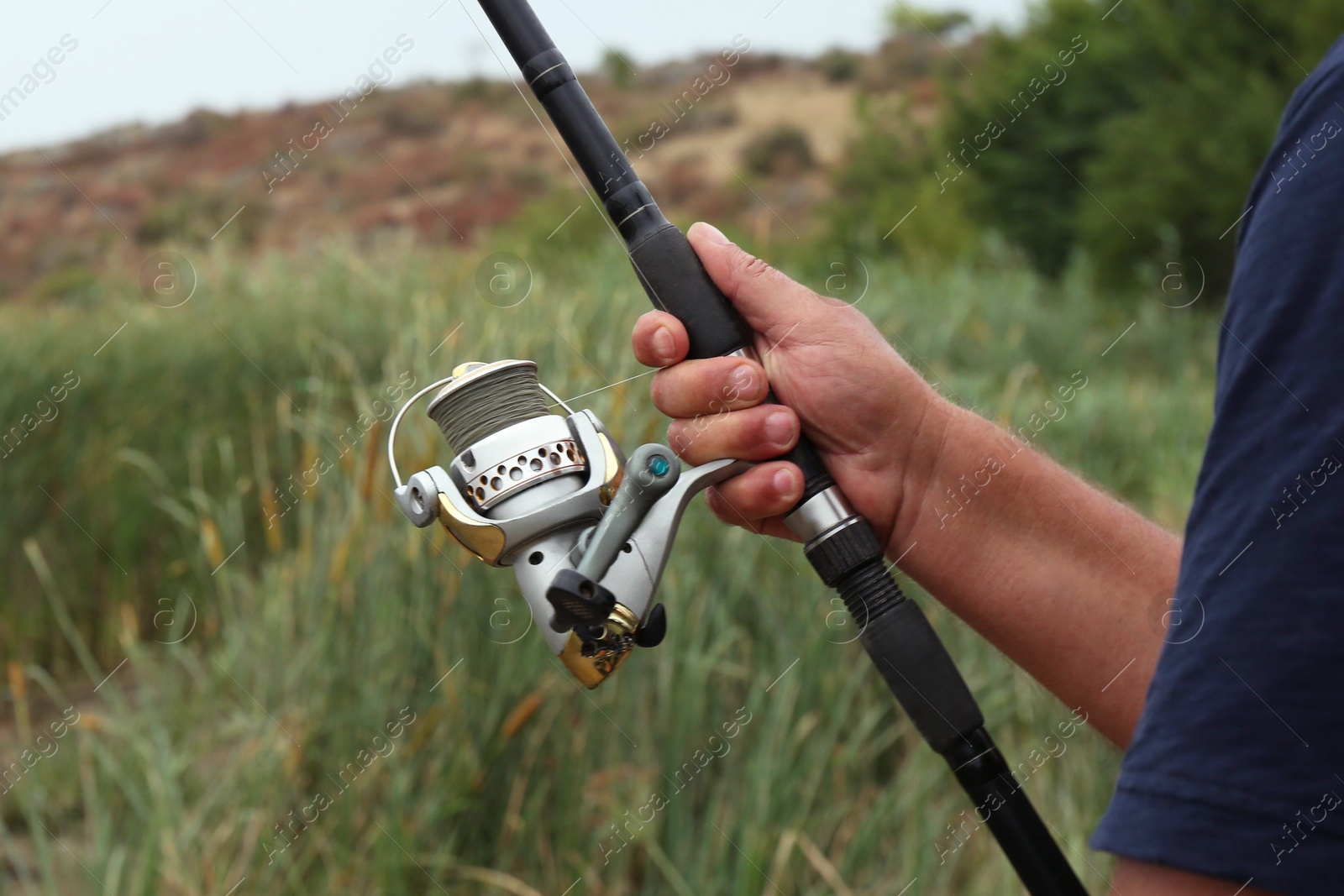 Photo of Fisherman with rod fishing near lake at summer, closeup