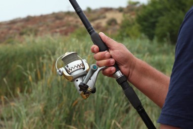 Fisherman with rod fishing near lake at summer, closeup