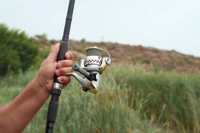 Fisherman with rod fishing near lake at summer, closeup