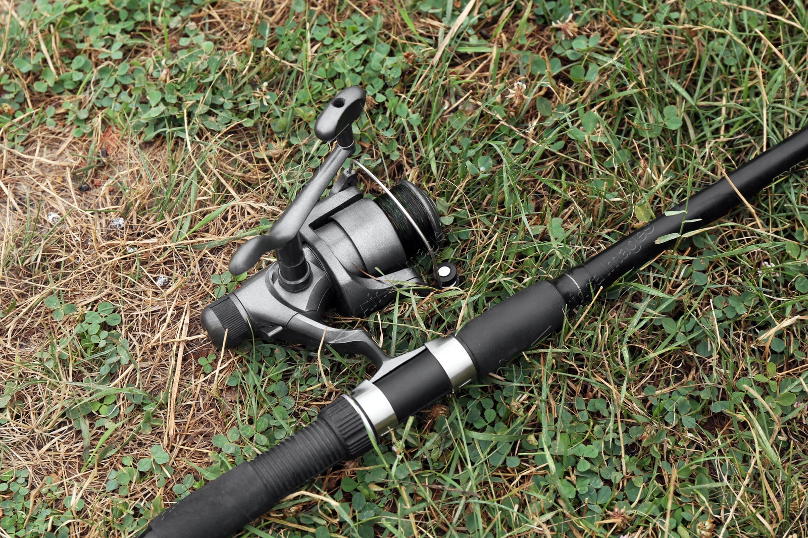 Photo of One fishing rod on green grass, above view