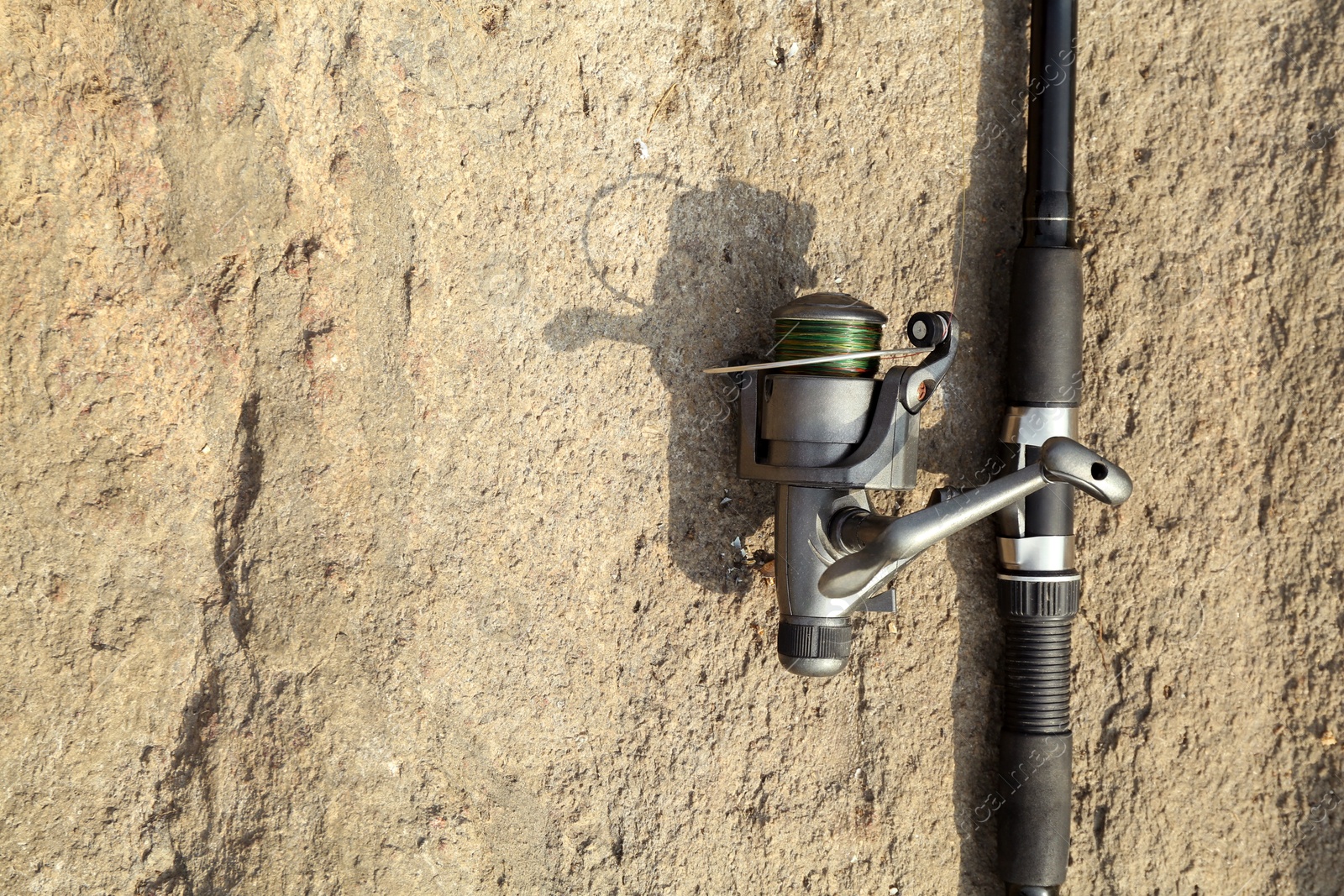 Photo of One fishing rod on ground outdoors, top view. Space for text