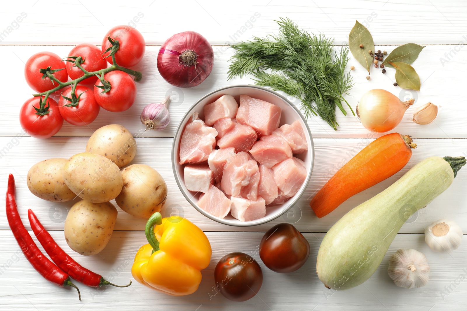 Photo of Uncooked ingredients for stew on white wooden table, flat lay