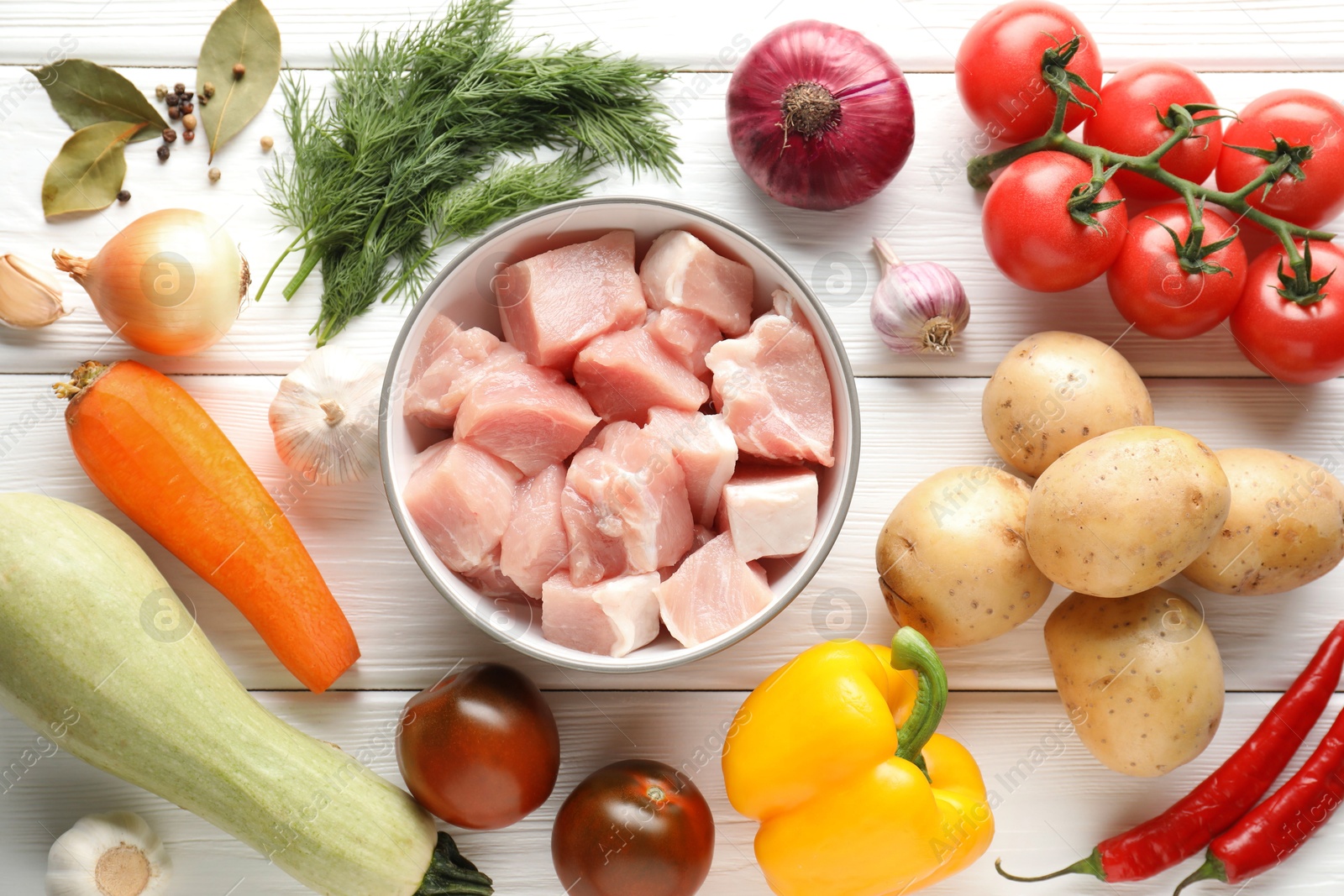 Photo of Uncooked ingredients for stew on white wooden table, flat lay