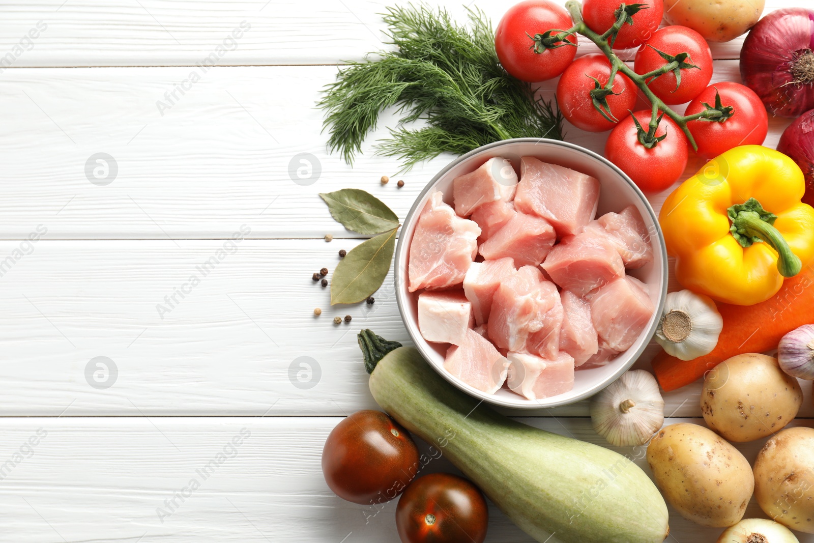 Photo of Uncooked ingredients for stew on white wooden table, flat lay. Space for text