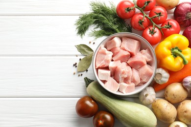 Photo of Uncooked ingredients for stew on white wooden table, flat lay. Space for text