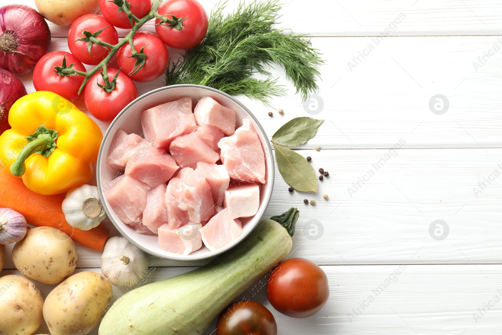 Photo of Uncooked ingredients for stew on white wooden table, flat lay. Space for text