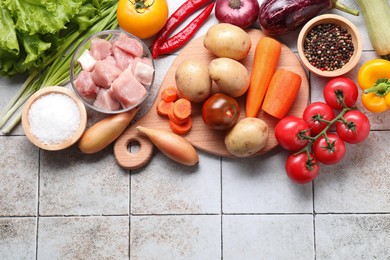 Photo of Uncooked ingredients for stew on tiled table, flat lay