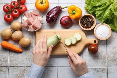 Photo of Woman cooking stew at tiled table, top view