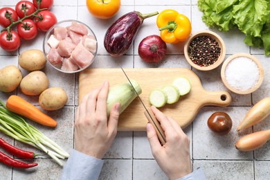 Photo of Woman cooking stew at tiled table, top view