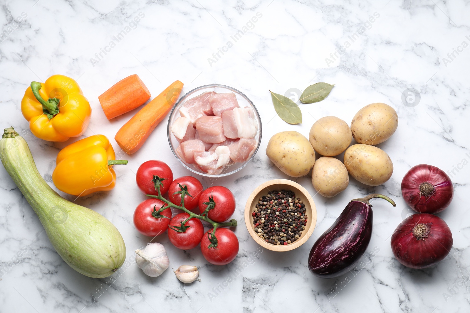 Photo of Uncooked ingredients for stew on white marble table, flat lay