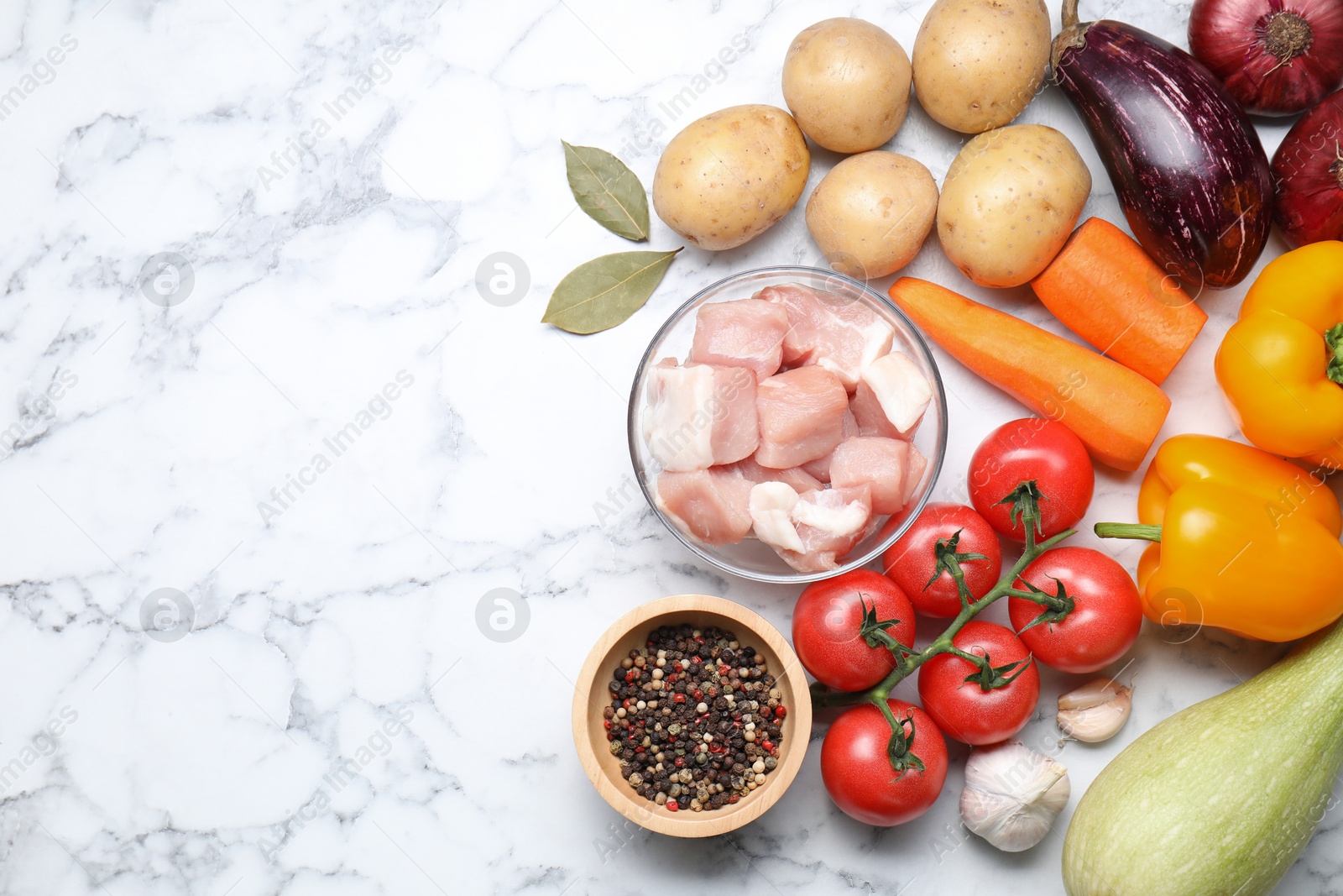 Photo of Uncooked ingredients for stew on white marble table, flat lay. Space for text