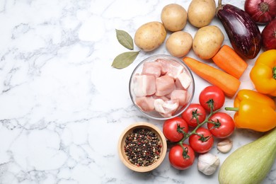 Photo of Uncooked ingredients for stew on white marble table, flat lay. Space for text