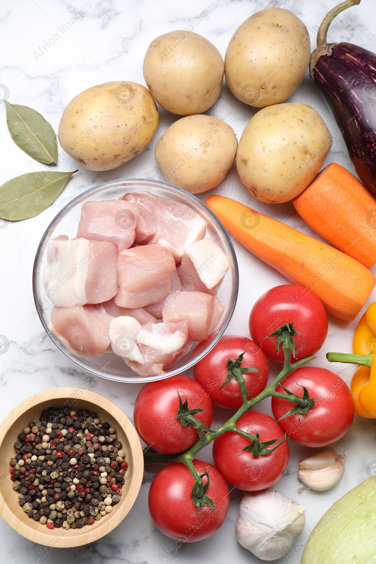 Photo of Uncooked ingredients for stew on white marble table, flat lay