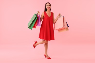 Photo of Smiling woman with colorful shopping bags on pink background